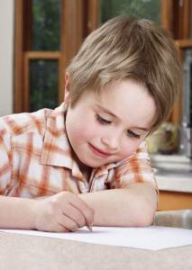 Young boy writing with pencil