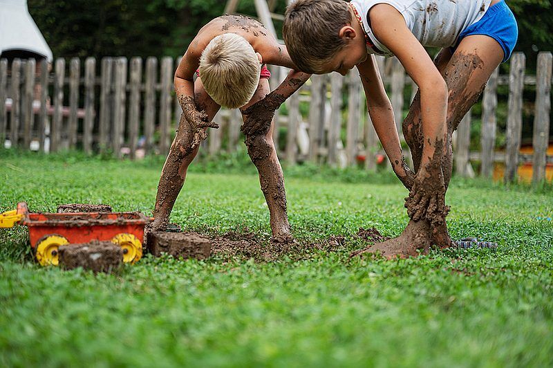 sensory challenges Two brothers playing with mud in their backyard spreading it all over themselves. Playing in the mud is a good exercise for a child with sensory challenges.