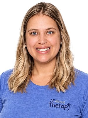 Portrait of a smiling woman wearing a blue All About Therapy, PLLC T-shirt, showcasing friendly, approachable therapy services.